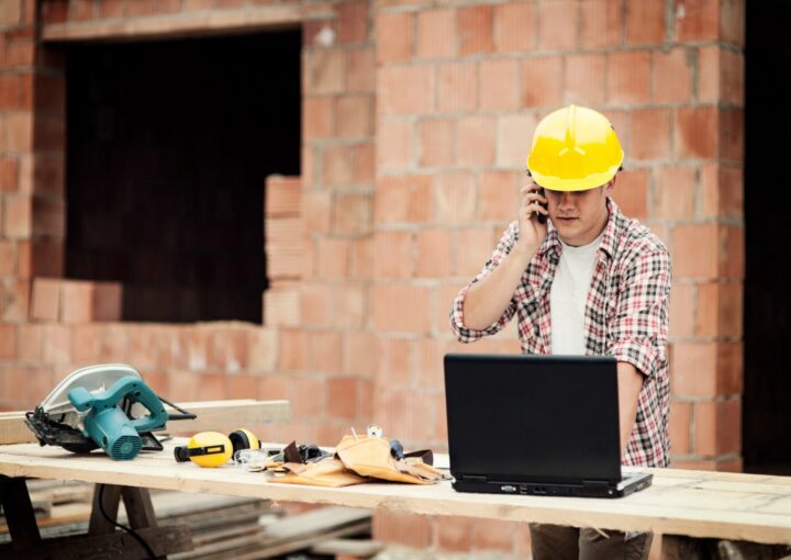 Tradie on a building site checking his laptop